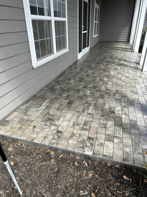 Porch with gray brick pavers, window, and siding.