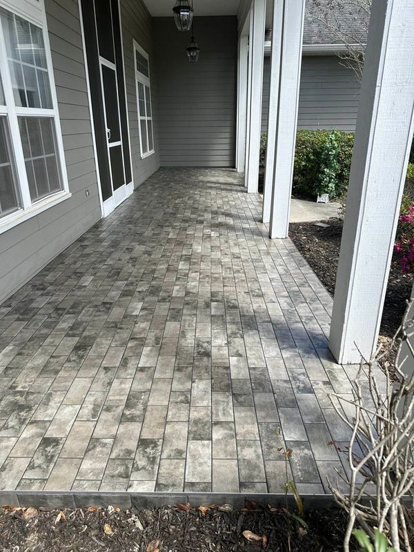 Gray brick paver porch with white columns and gray siding.
