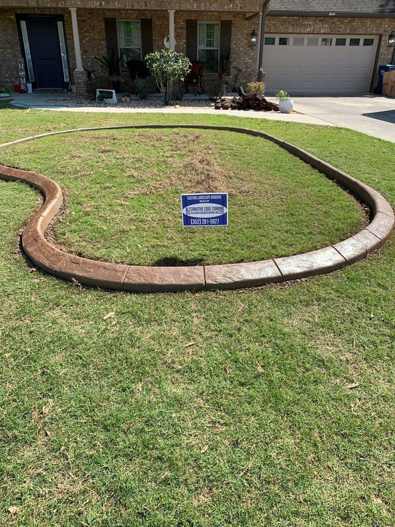 Brown concrete landscape curbing in front yard, bordering grass.
