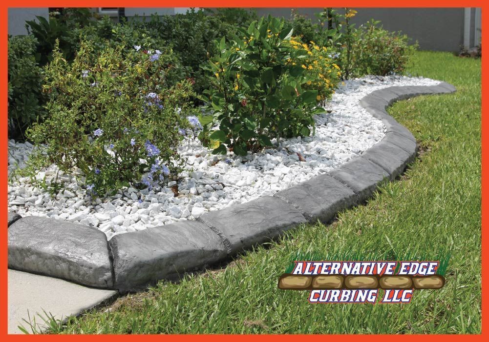 Gray concrete curbing bordering a flower bed with white gravel.