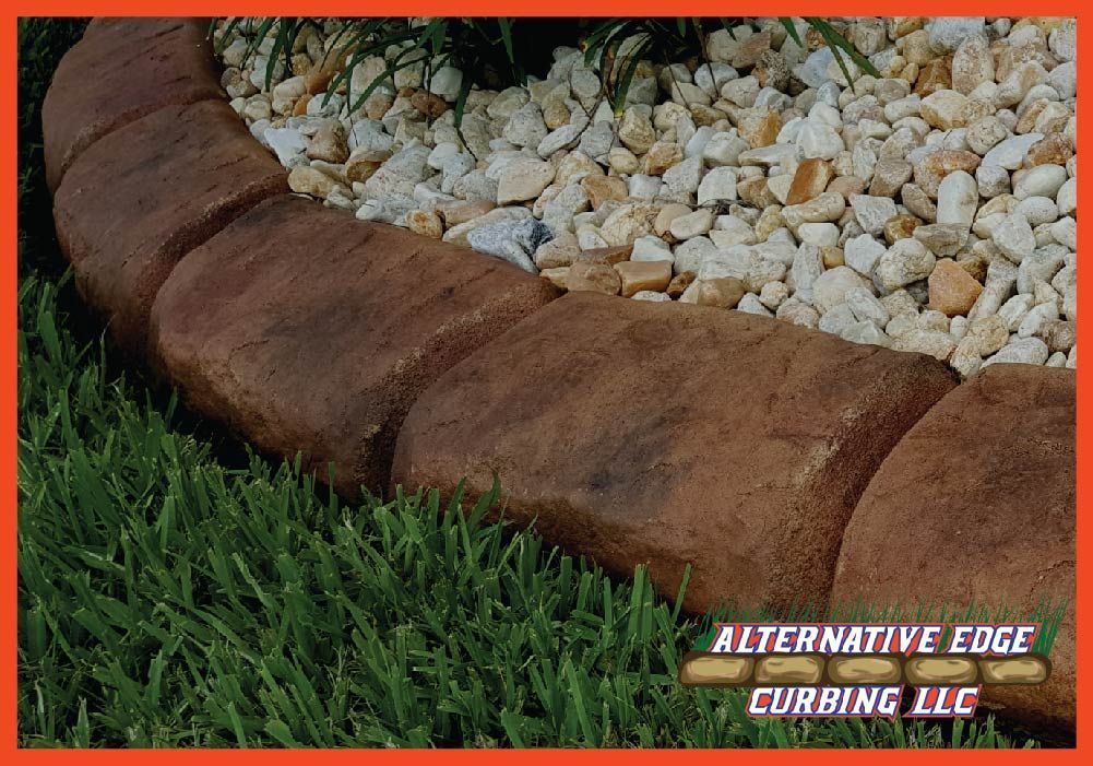 Brown stone curbing borders a grassy area and a bed of white rocks.