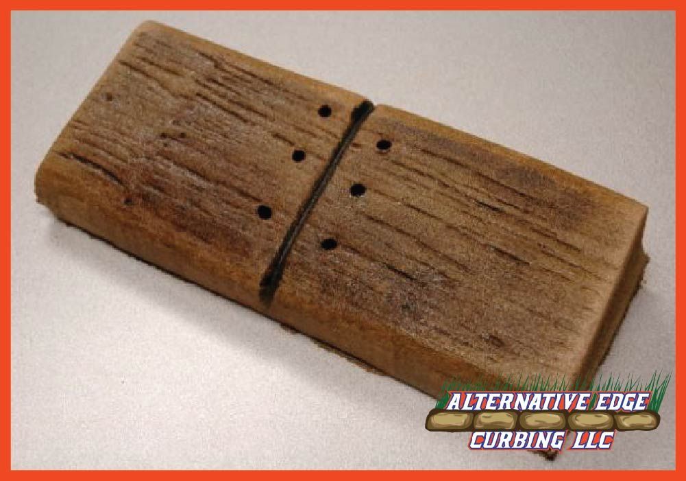 Brown, weathered, rectangular landscaping curb segment; two connected pieces with simulated wood grain and bolt holes.