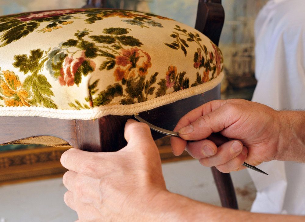 A Person Is Working On A Chair With A Floral Cushion — Coastal Upholstery In Berkeley Vale, NSW