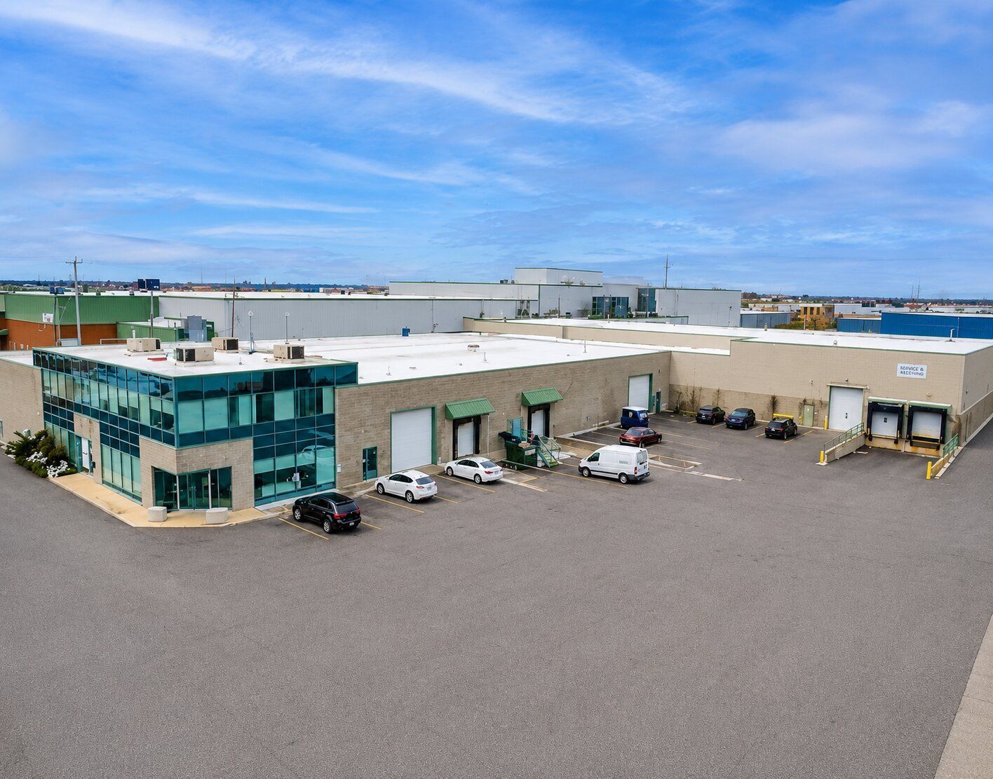 Vue aérienne d'une cour d'entrepôt industriel avec des camions, des quais de chargement et un immeuble de bureaux vitré