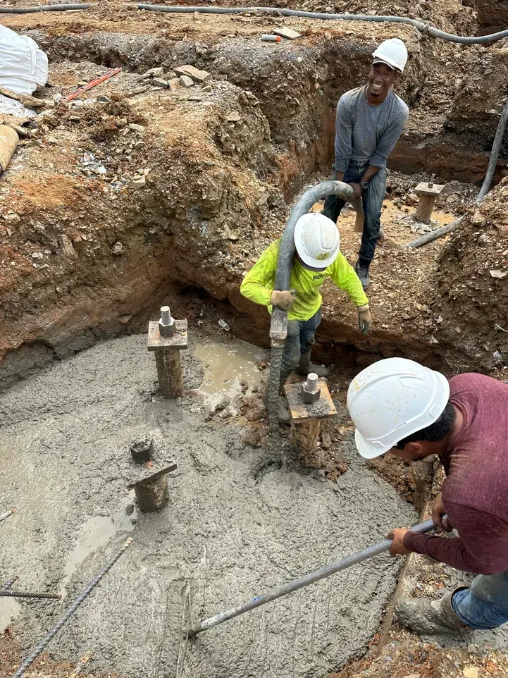 Yellow excavator demolishing a two-story house, debris scattered, blue sky background.
