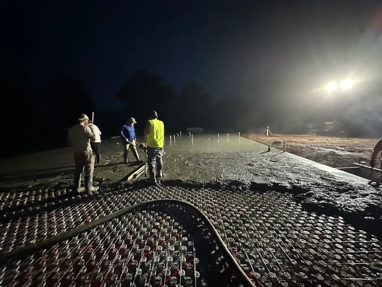 Excavator demolishing a white building against a clear blue sky; debris scattered.