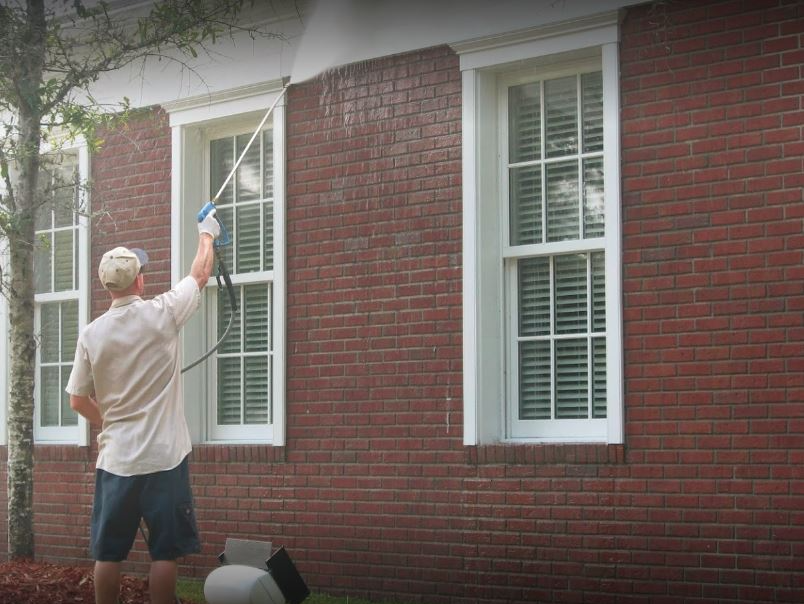 man standing and pressure cleaning a soffit