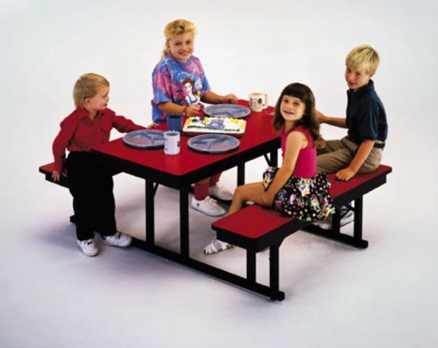 A group of children are sitting at a red picnic table