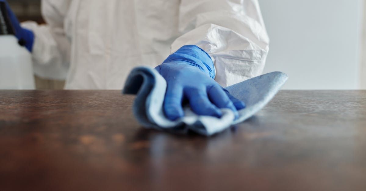 A person wearing blue gloves is cleaning a table with a cloth.