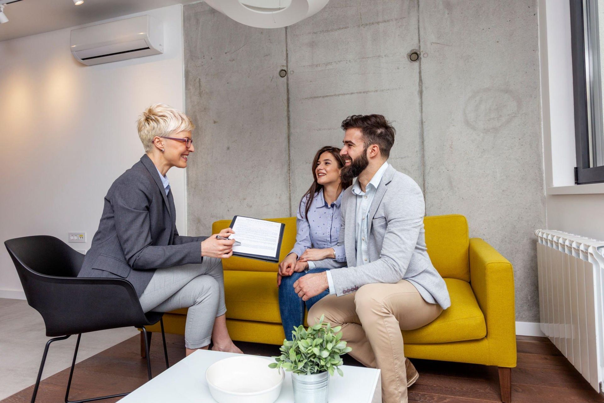 A woman is sitting on a couch talking to a man and woman.