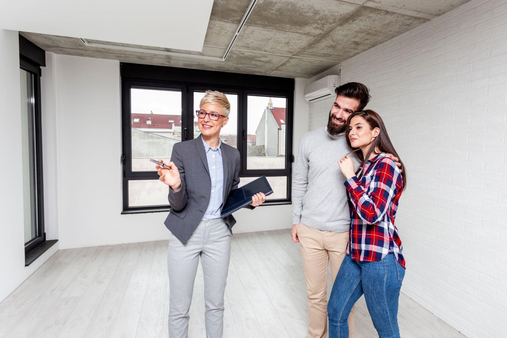 A woman is standing next to a man and woman in an empty room.