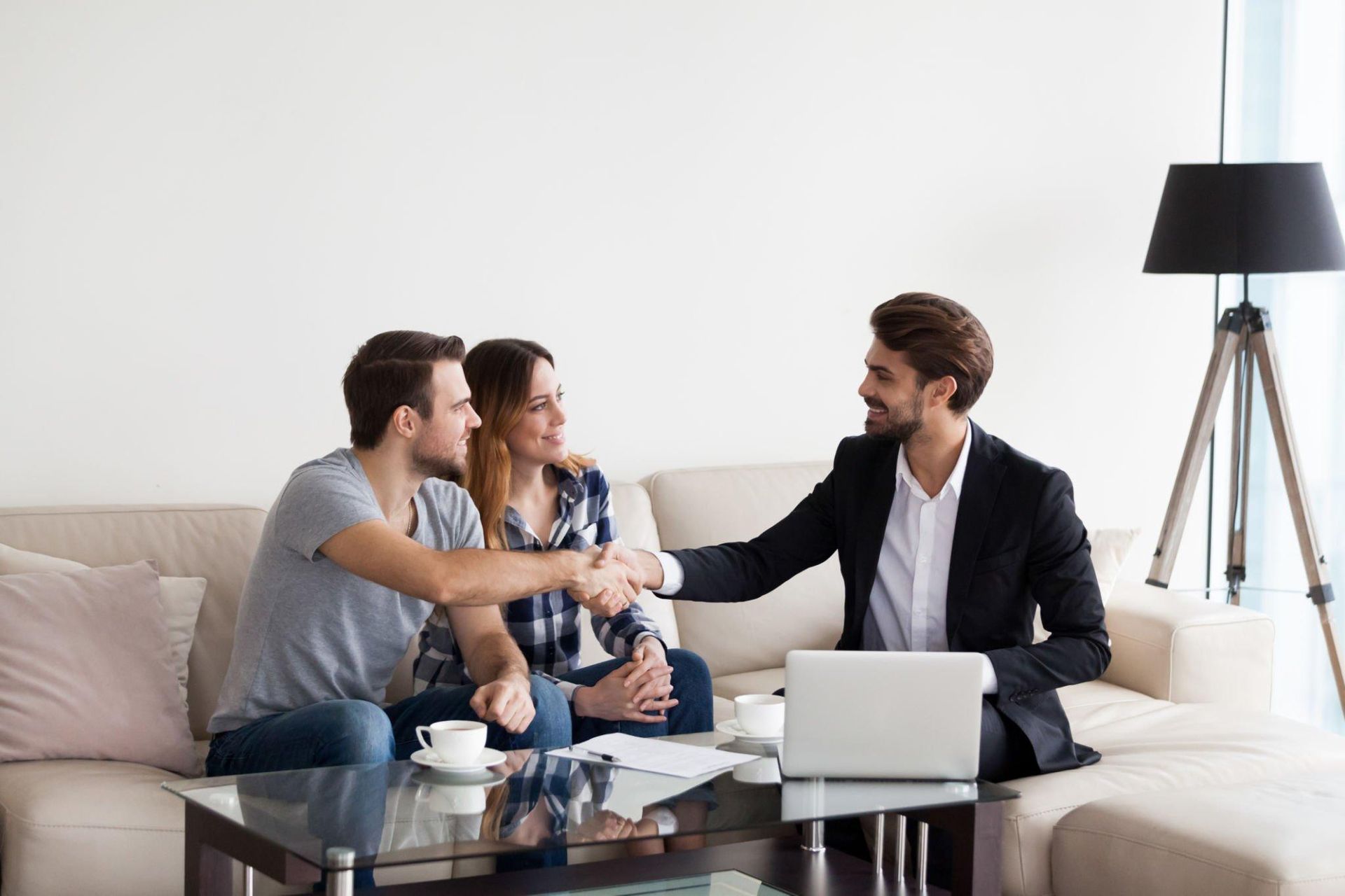 A man is shaking hands with a couple sitting on a couch.