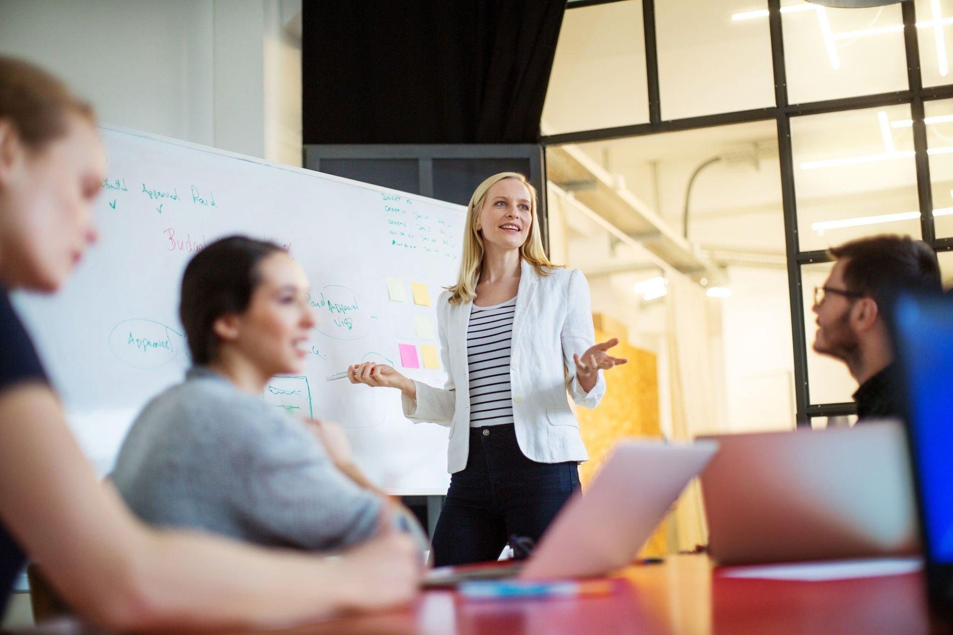 A woman is giving a presentation to a group of people in a conference room.