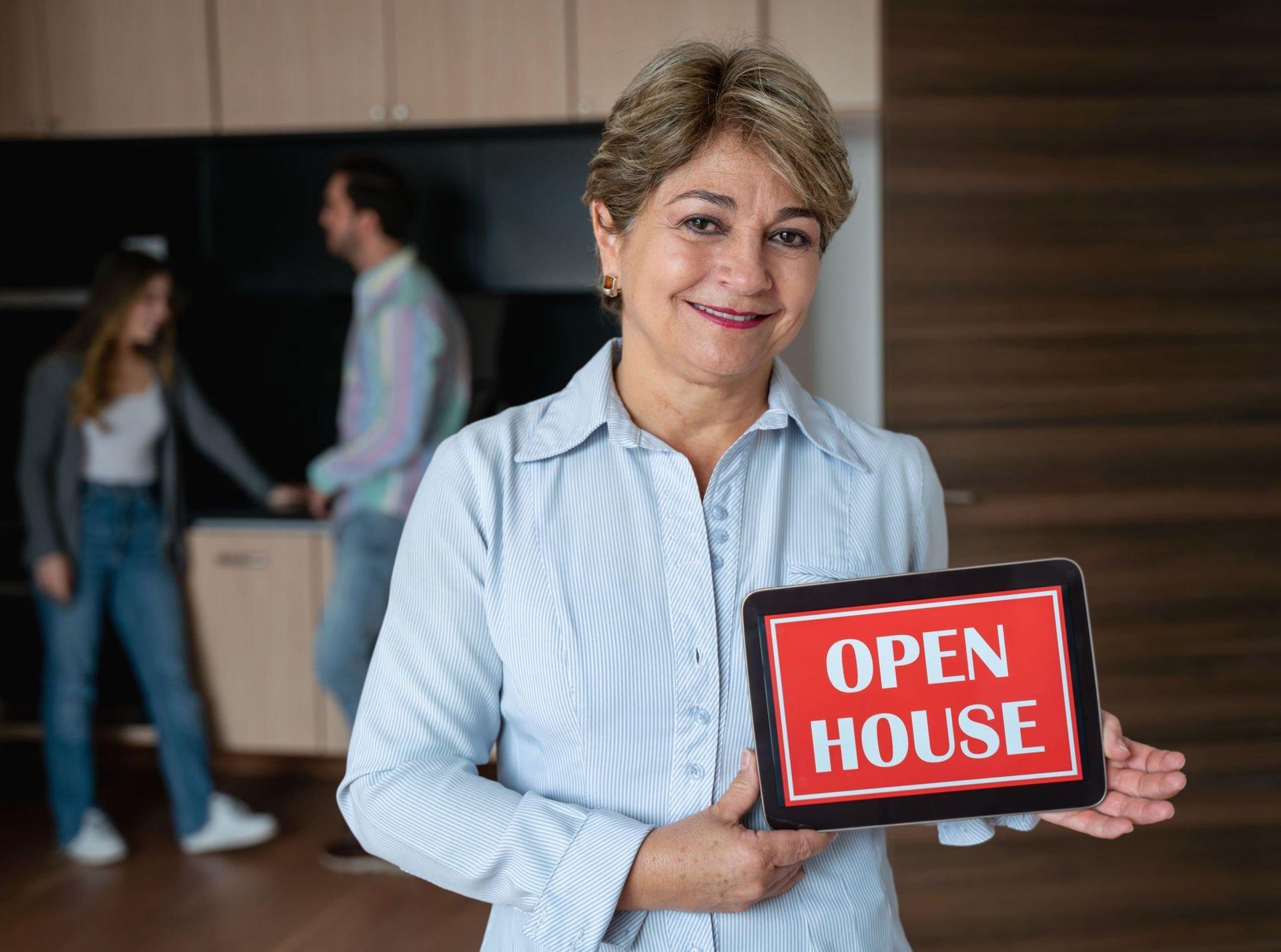 A woman is holding a tablet with an open house sign on it.