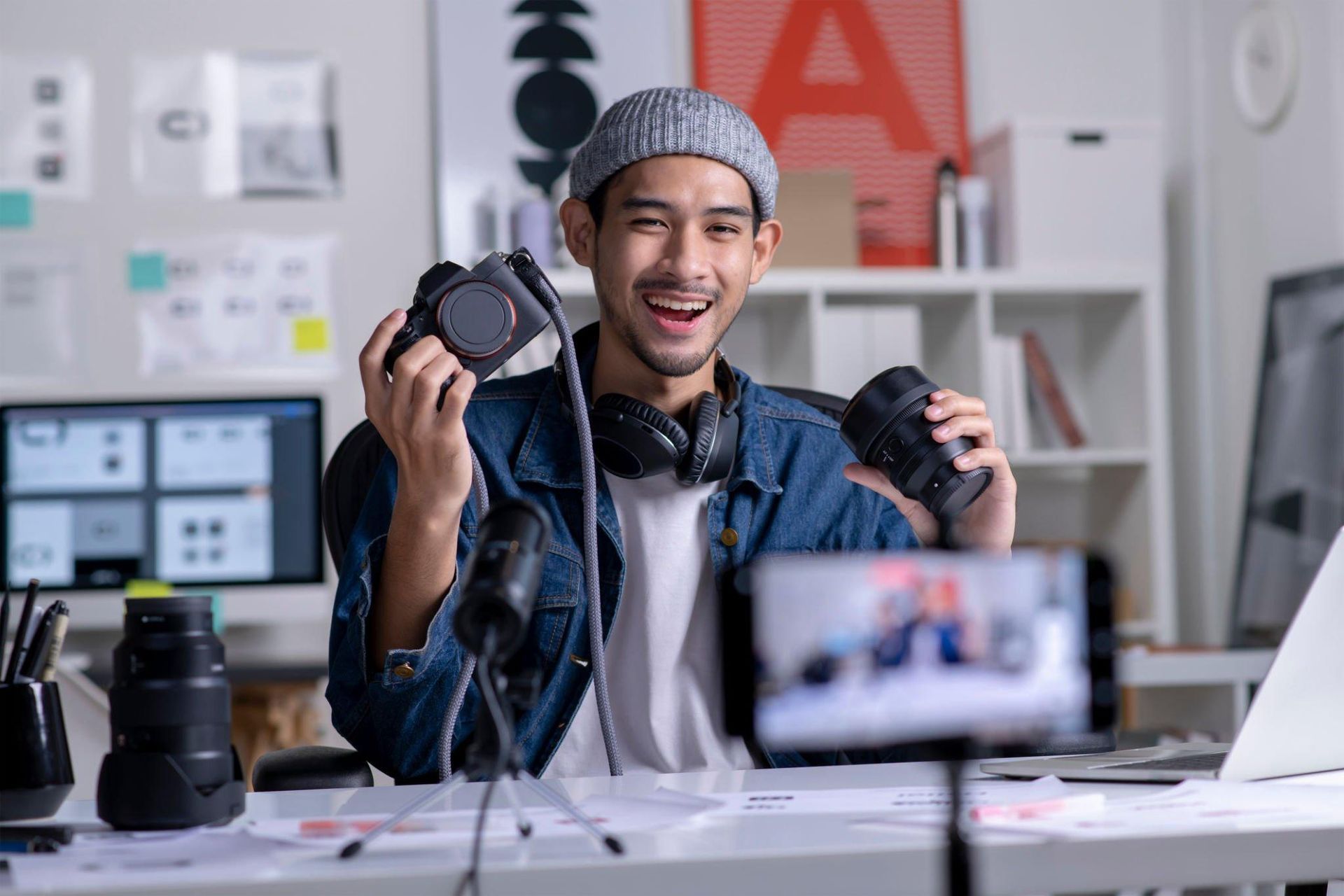 A man is holding two cameras in front of a camera.