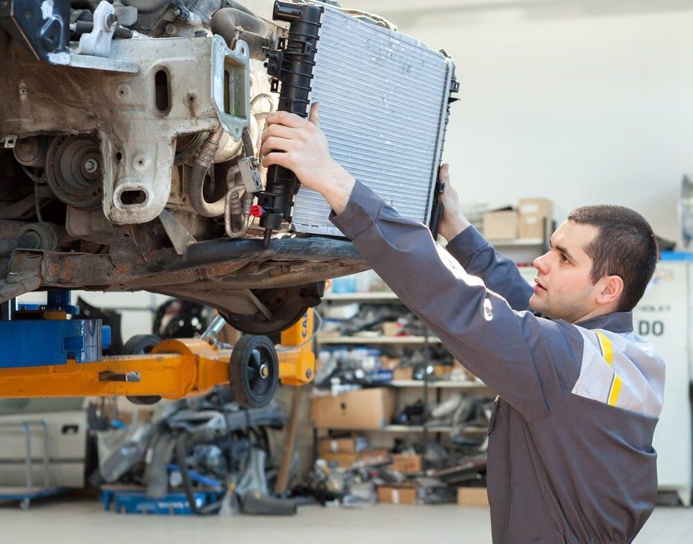 A Man is Working on a Car Radiator in a Garage — Quick Fix Automotive in Ballina, NSW