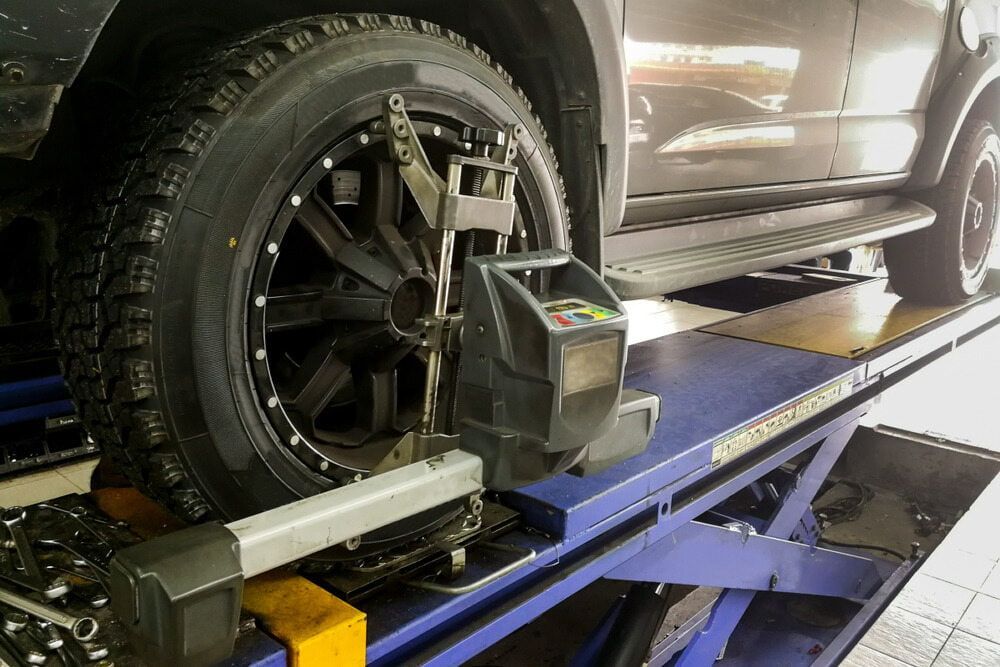 Car Wheel Undergoing Alignment on a Blue Lift — Autopro Taree in Taree, NSW