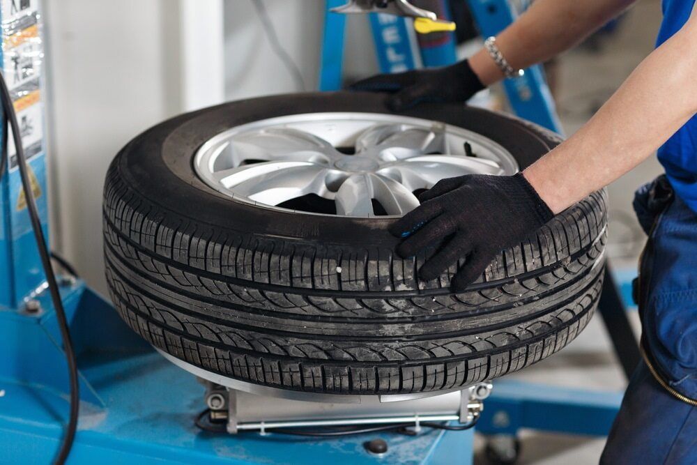 Person in Blue Shirt Changing a Tire on a Machine; Tire is Black, Rim Silver — Autopro Taree in Taree, NSW