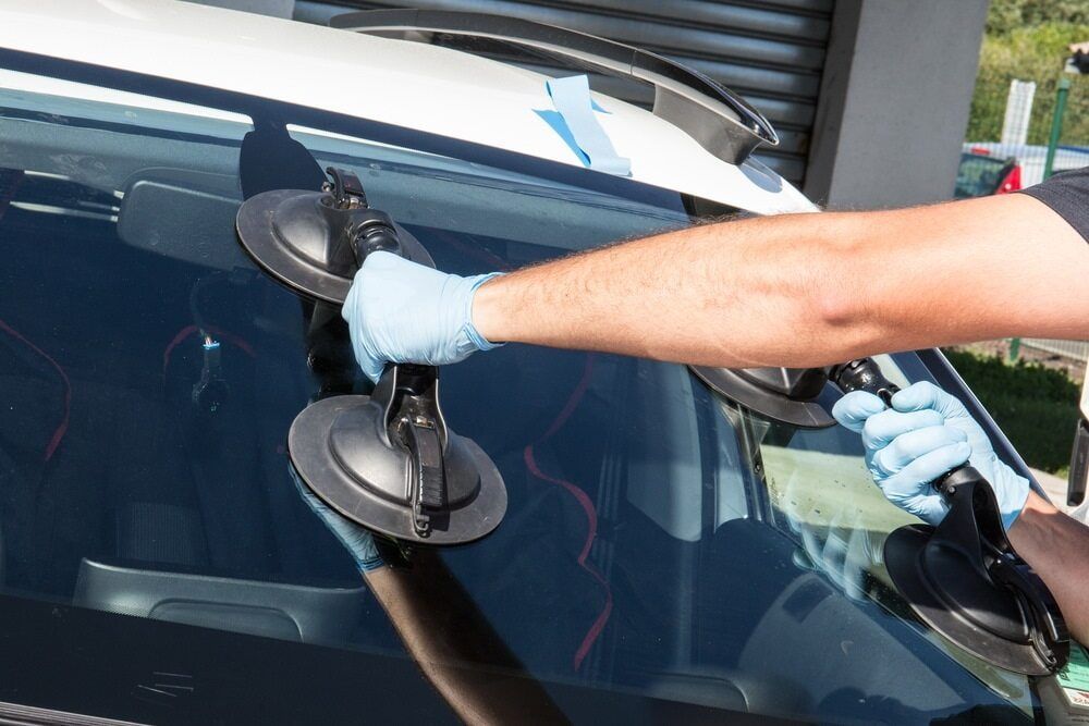 Person Using Suction Cups to Remove a Car Windshield. Hands in Blue Gloves — Autopro Taree in Taree, NSW