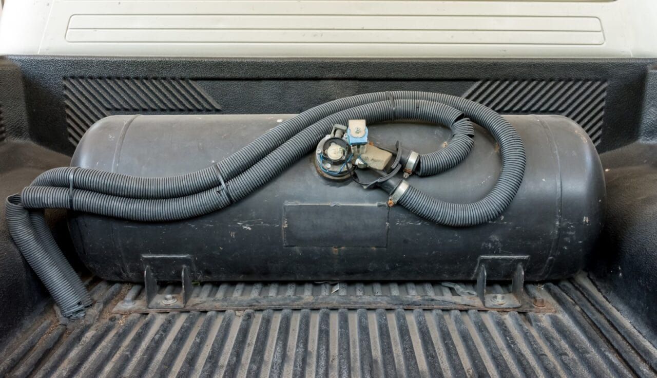 Black Propane Tank in a Truck Bed, With Connecting Hoses and a Control Valve — Autopro Taree in Taree, NSW