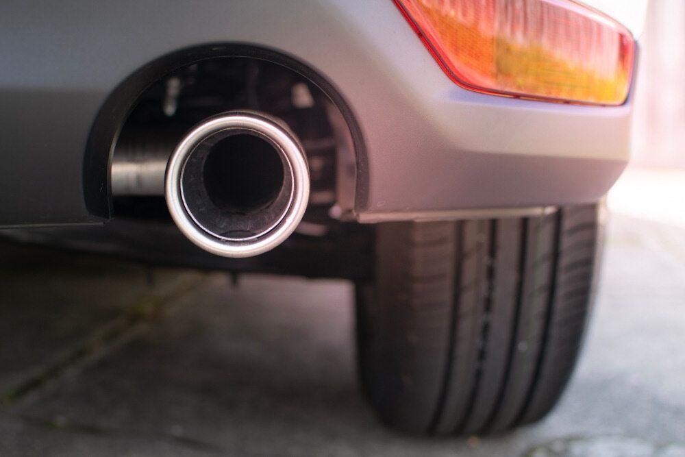 Exhaust Pipe of a Gray Car, Next to a Tire and Tail Light — Autopro Taree in Taree, NSW