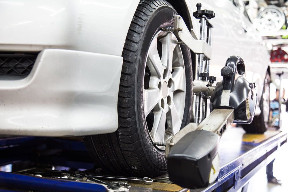 A White Car Wheel Undergoing an Alignment Test in a Repair Shop — Autopro Taree in Taree, NSW