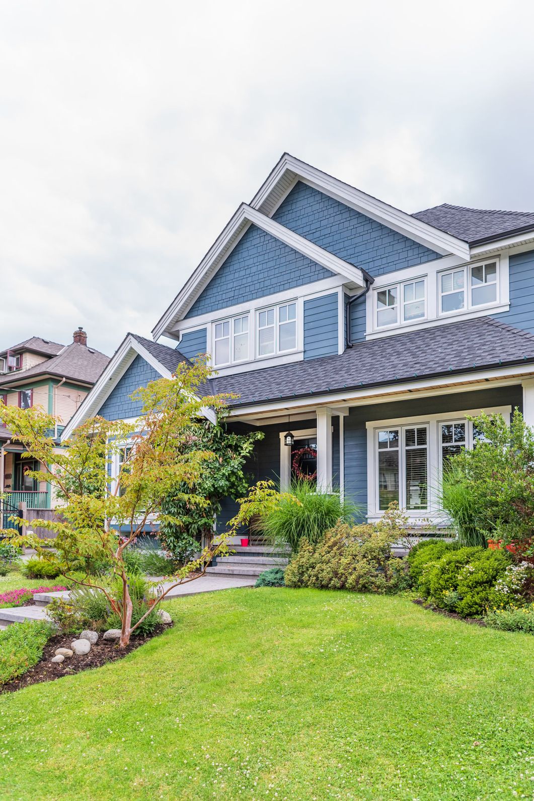 A large blue house with a lush green lawn in front of it.