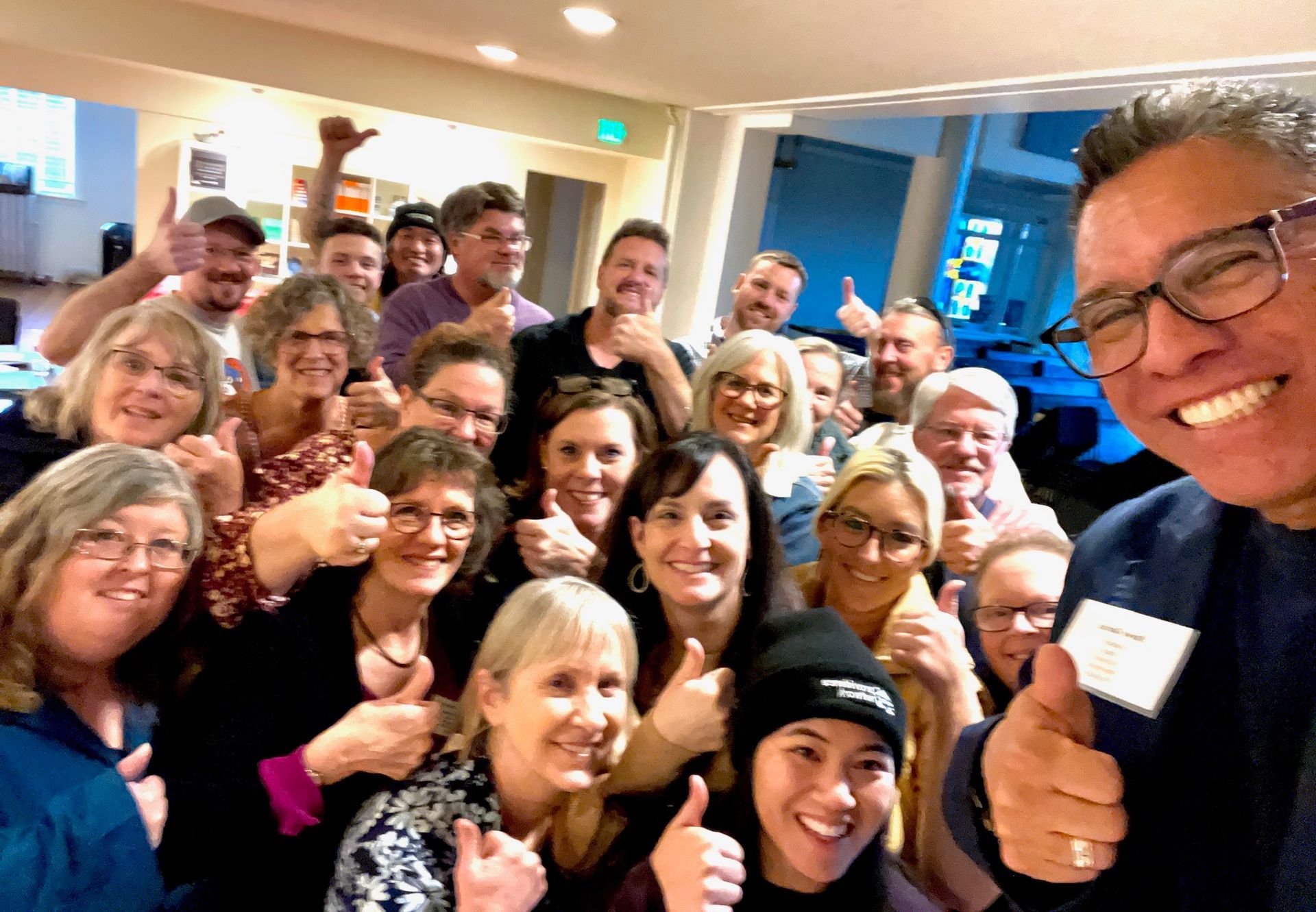 A group of people are posing for a picture and giving a thumbs up.