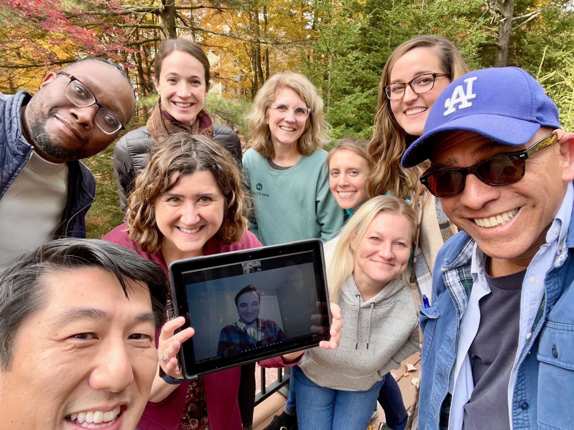 A group of people are posing for a picture while holding a tablet.