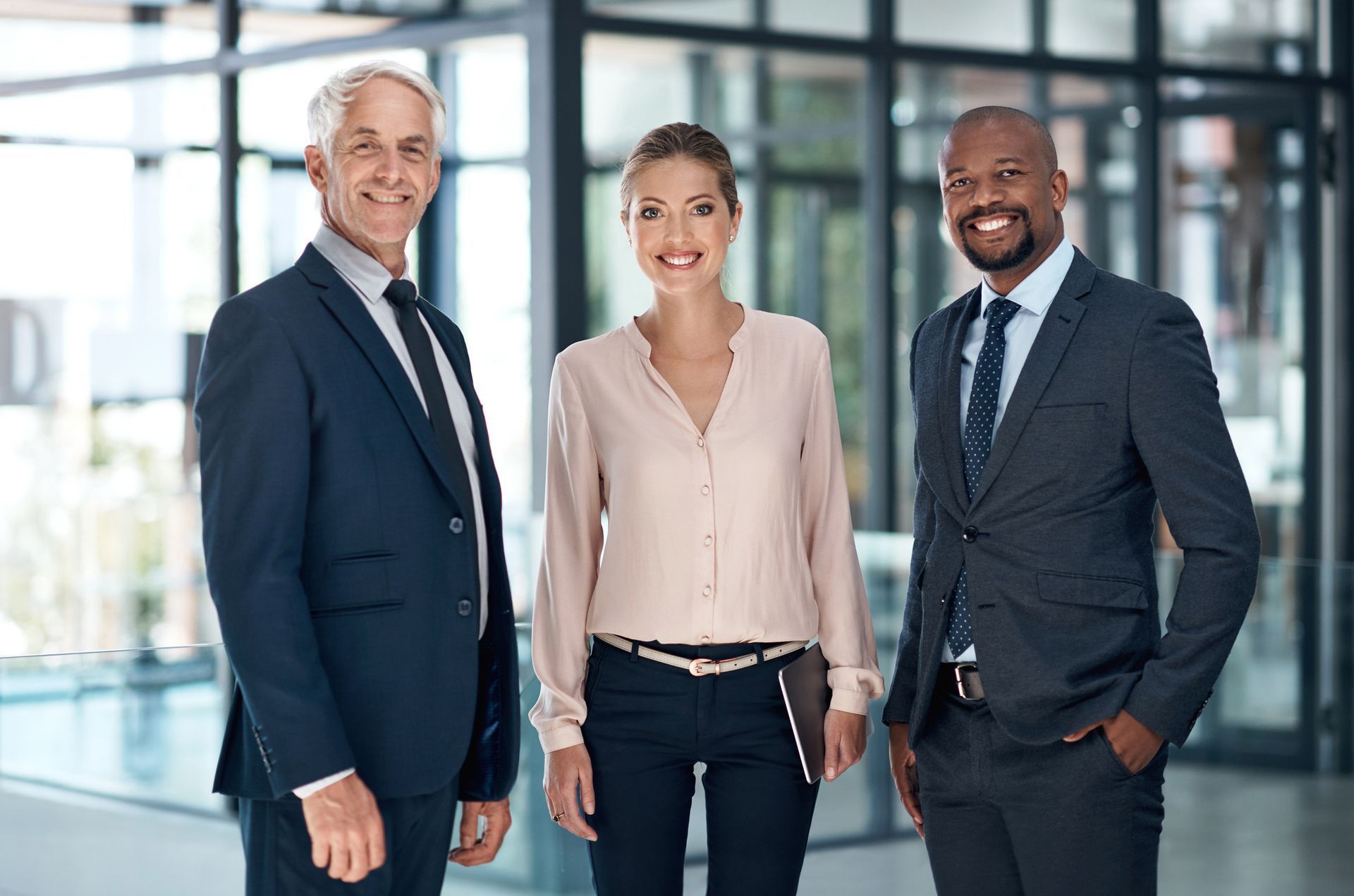Three business people are standing next to each other in an office.