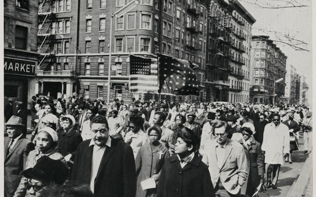 A black and white photo of a crowd of people walking down a street.