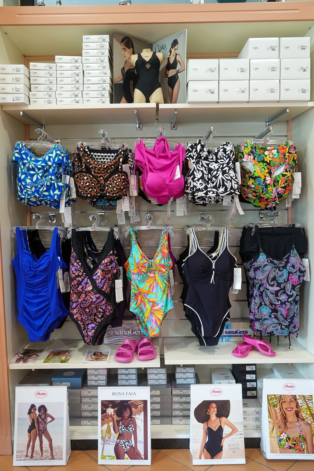 Costumi da bagno esposti sugli scaffali di un negozio, di vari colori e fantasie.