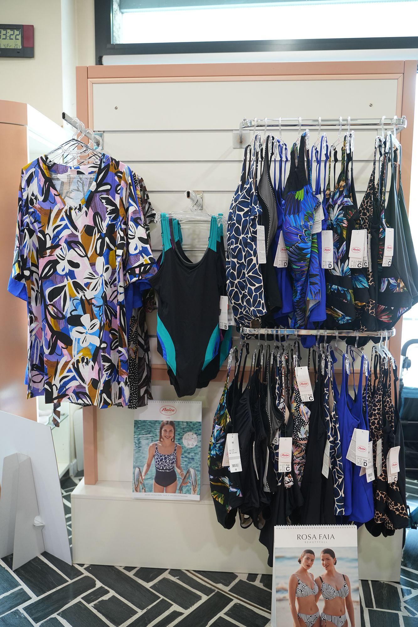 Esposizione di costumi da bagno in un negozio, compresi costumi da bagno e copricostumi appesi su grucce.