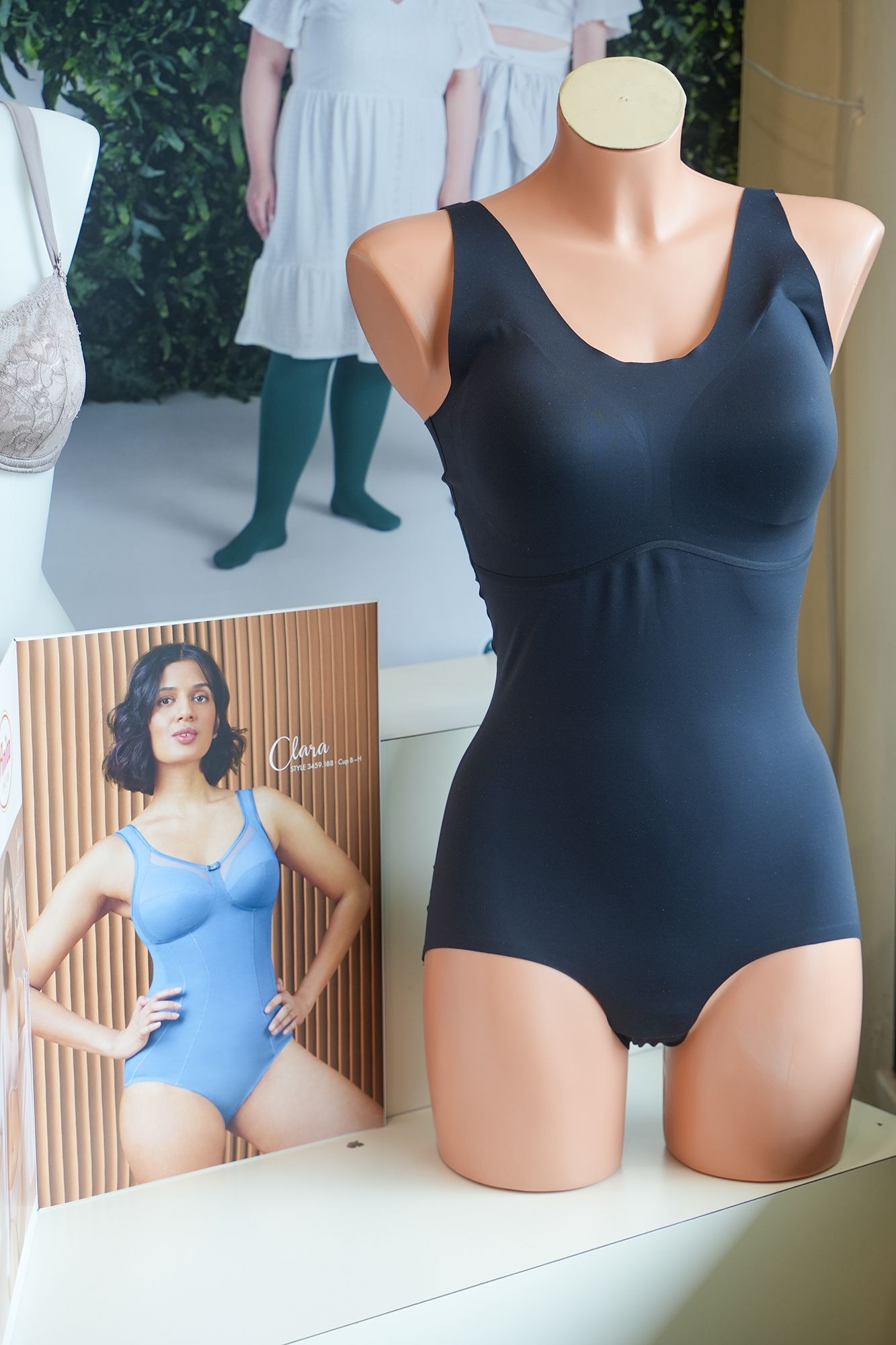 Una tuta nera su un manichino, con un poster di una donna che indossa una tuta blu.