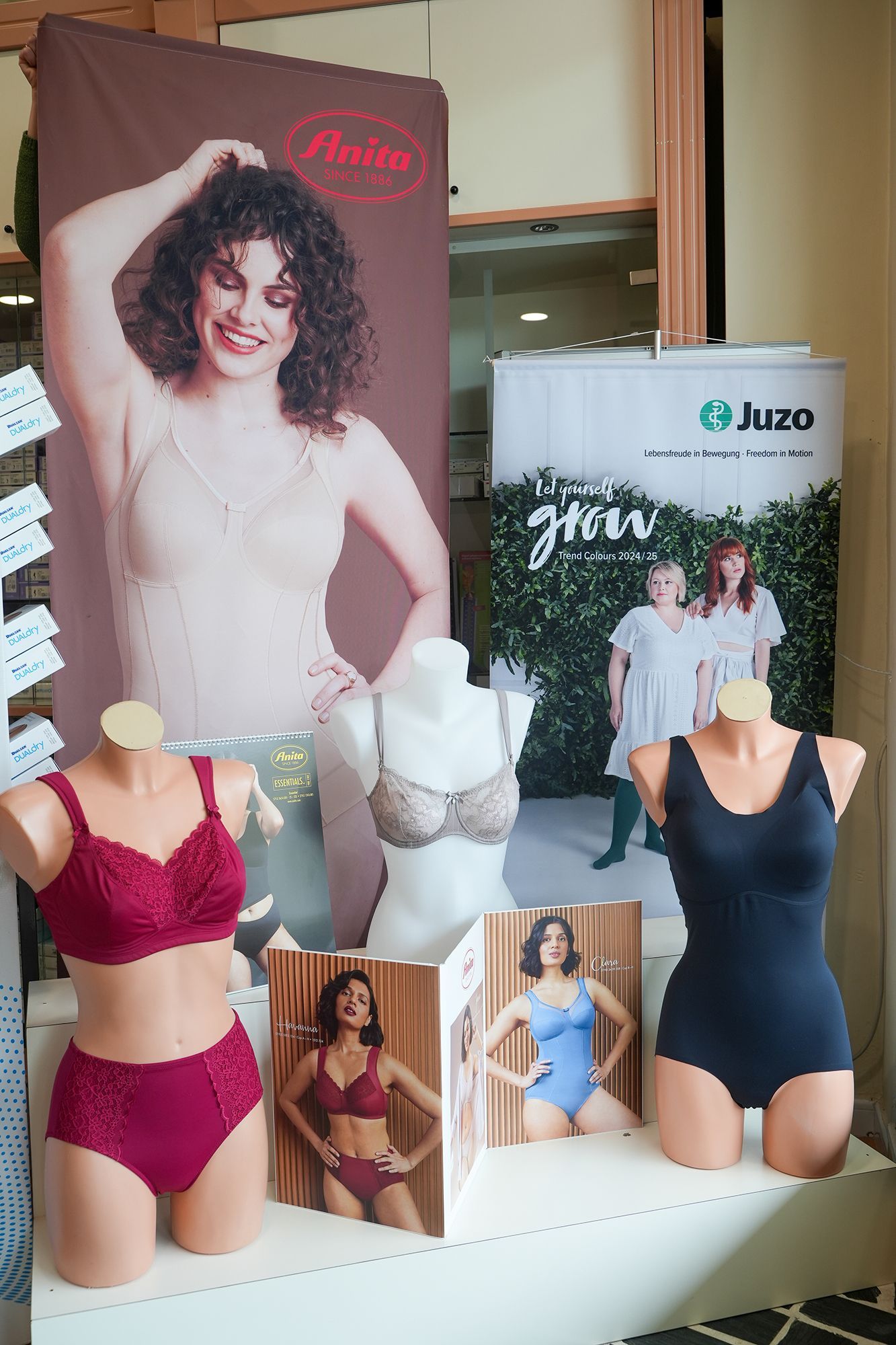 Espositore di lingerie con manichini che mostrano reggiseni e biancheria intima; banner pubblicitari sullo sfondo.