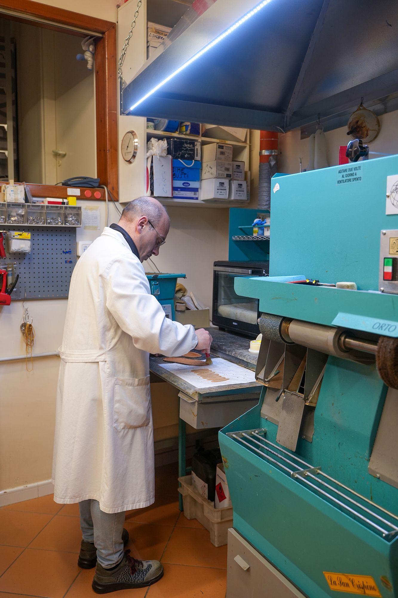 Uomo in camice bianco al lavoro su un macchinario in officina.