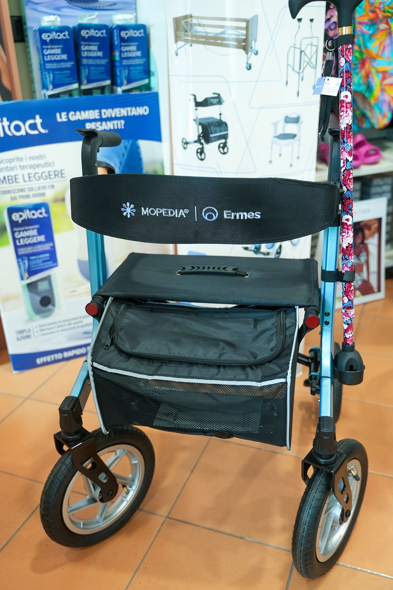 Deambulatore blu e nero con sedile, borsa e maniglia con motivo floreale.