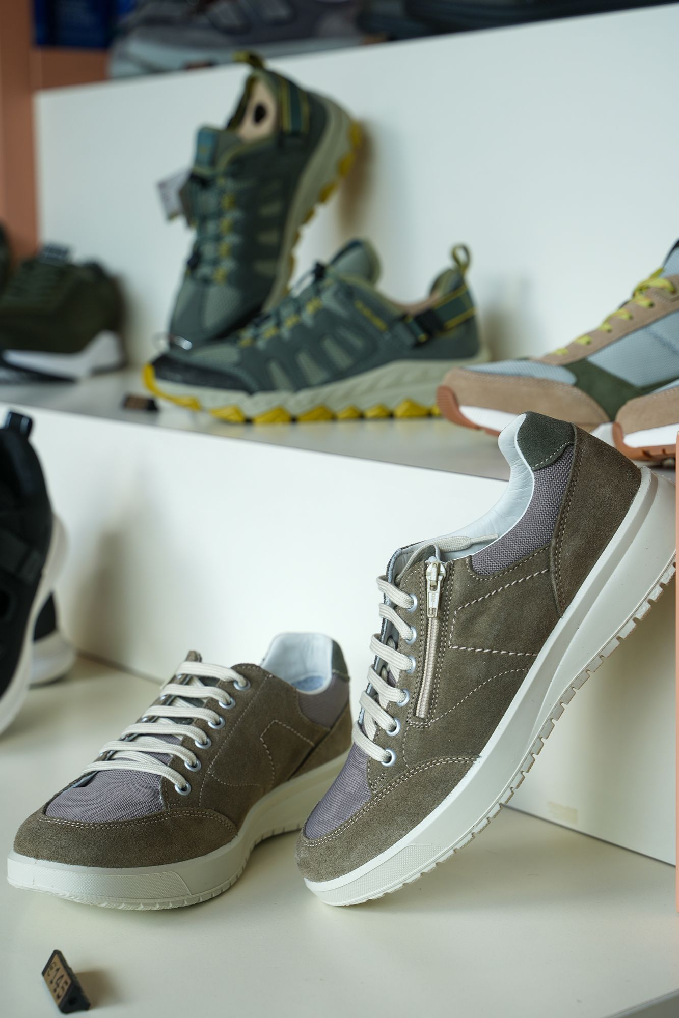 Scarpe esposte in un negozio, tra cui scarpe da ginnastica e da trekking di vari colori.