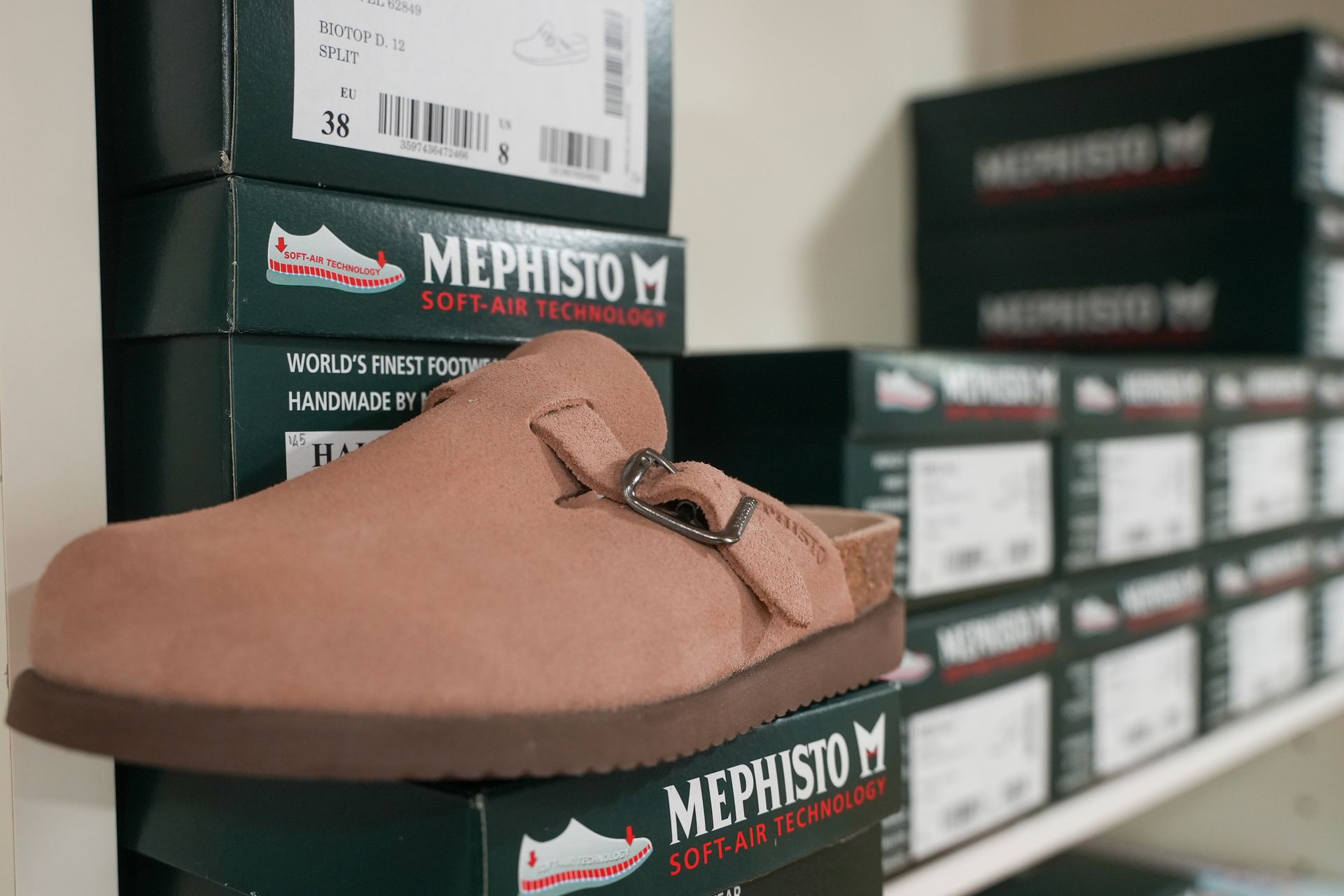 Zoccoli Mephisto in pelle scamosciata color cuoio, imballati in scatole in un negozio.