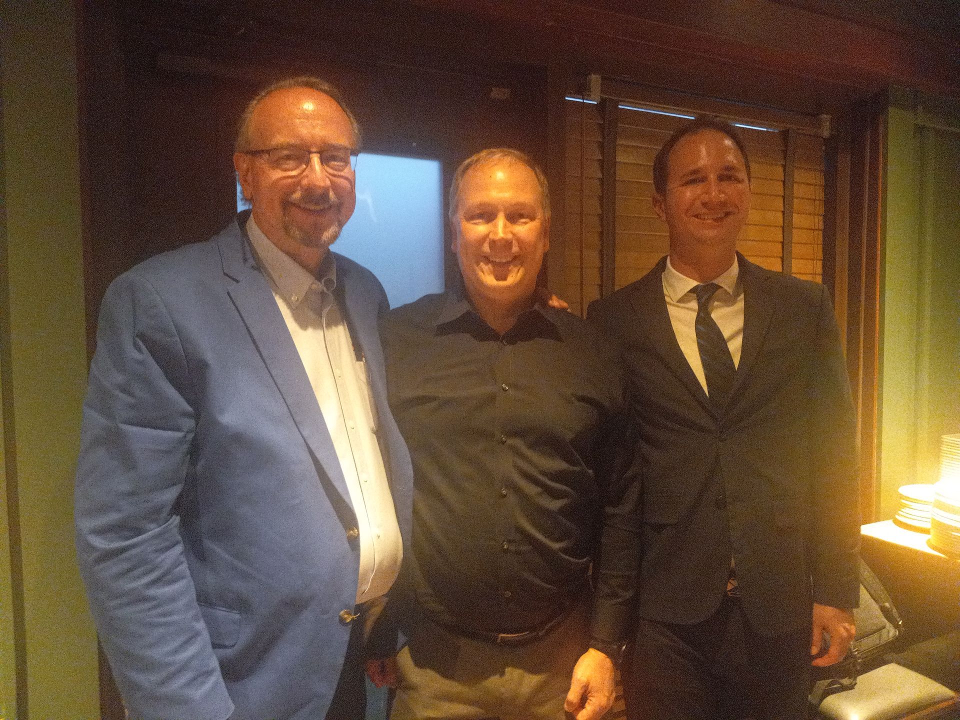 Three men in suits are posing for a picture together