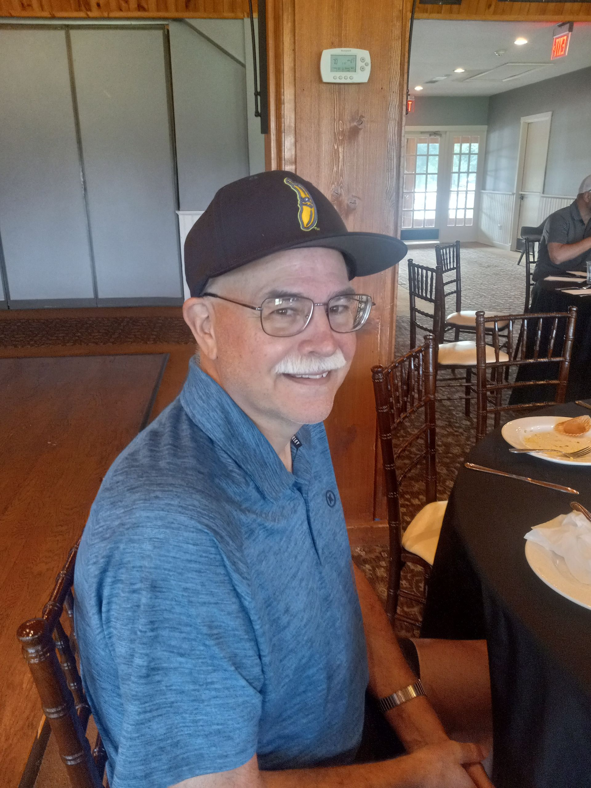 A man wearing a hat and glasses is sitting at a table