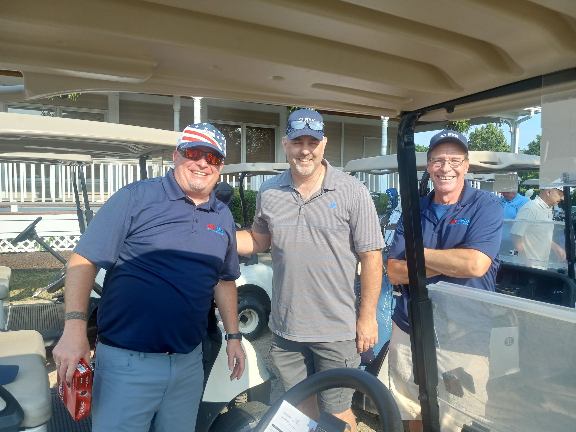 Three men are posing for a picture in a golf cart.