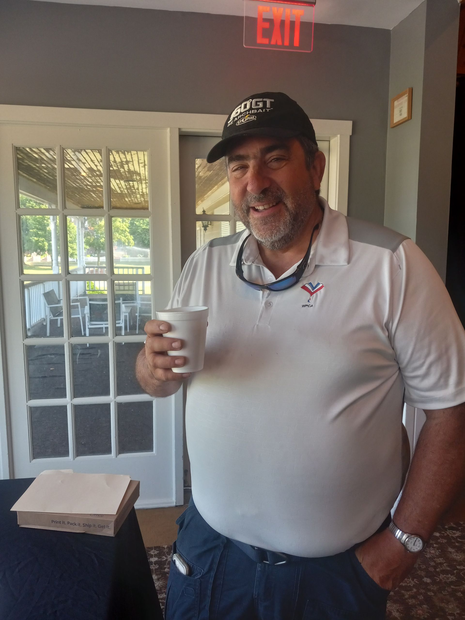 A man holding a cup in front of an exit sign