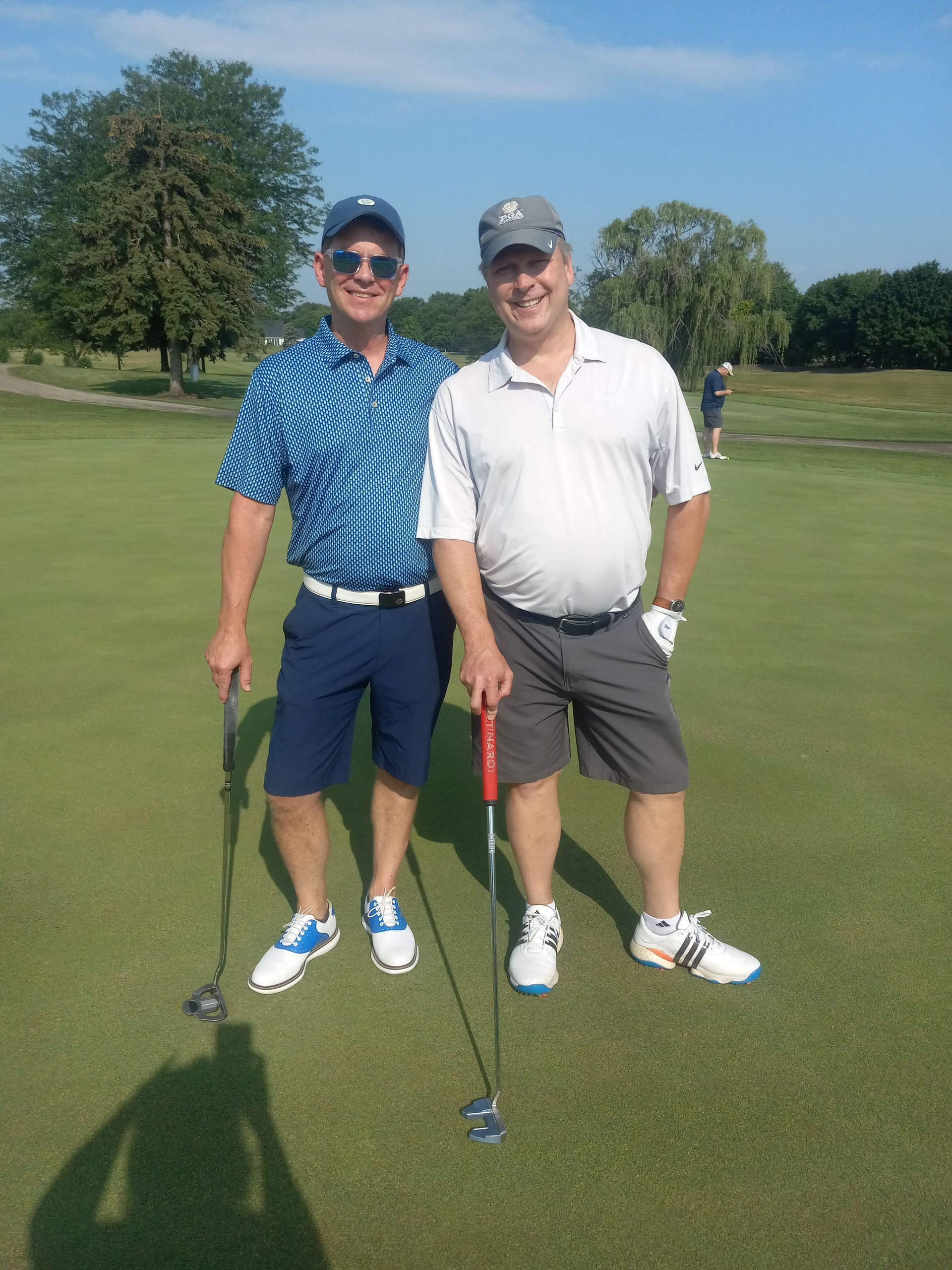 Two men standing on a golf course holding golf clubs