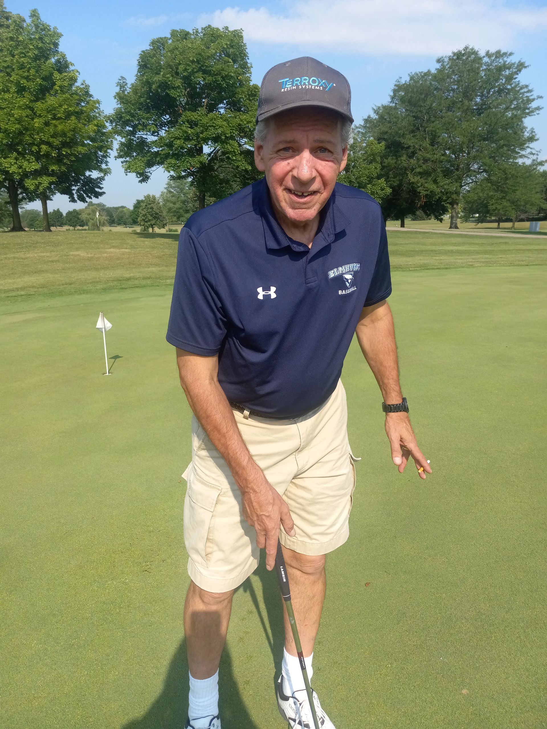 A man is standing on a golf course holding a golf club.