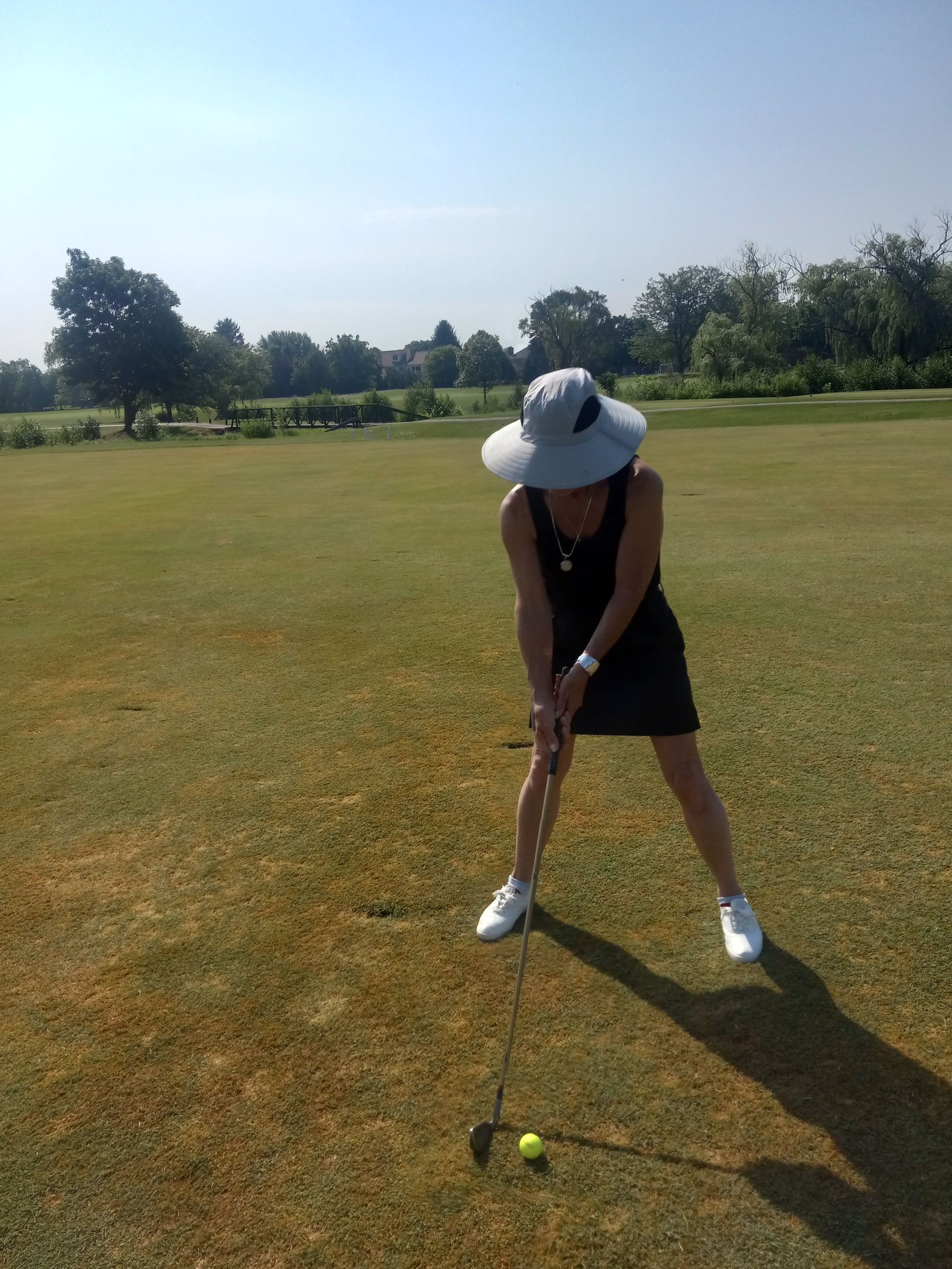 A woman in a hat is swinging a golf club