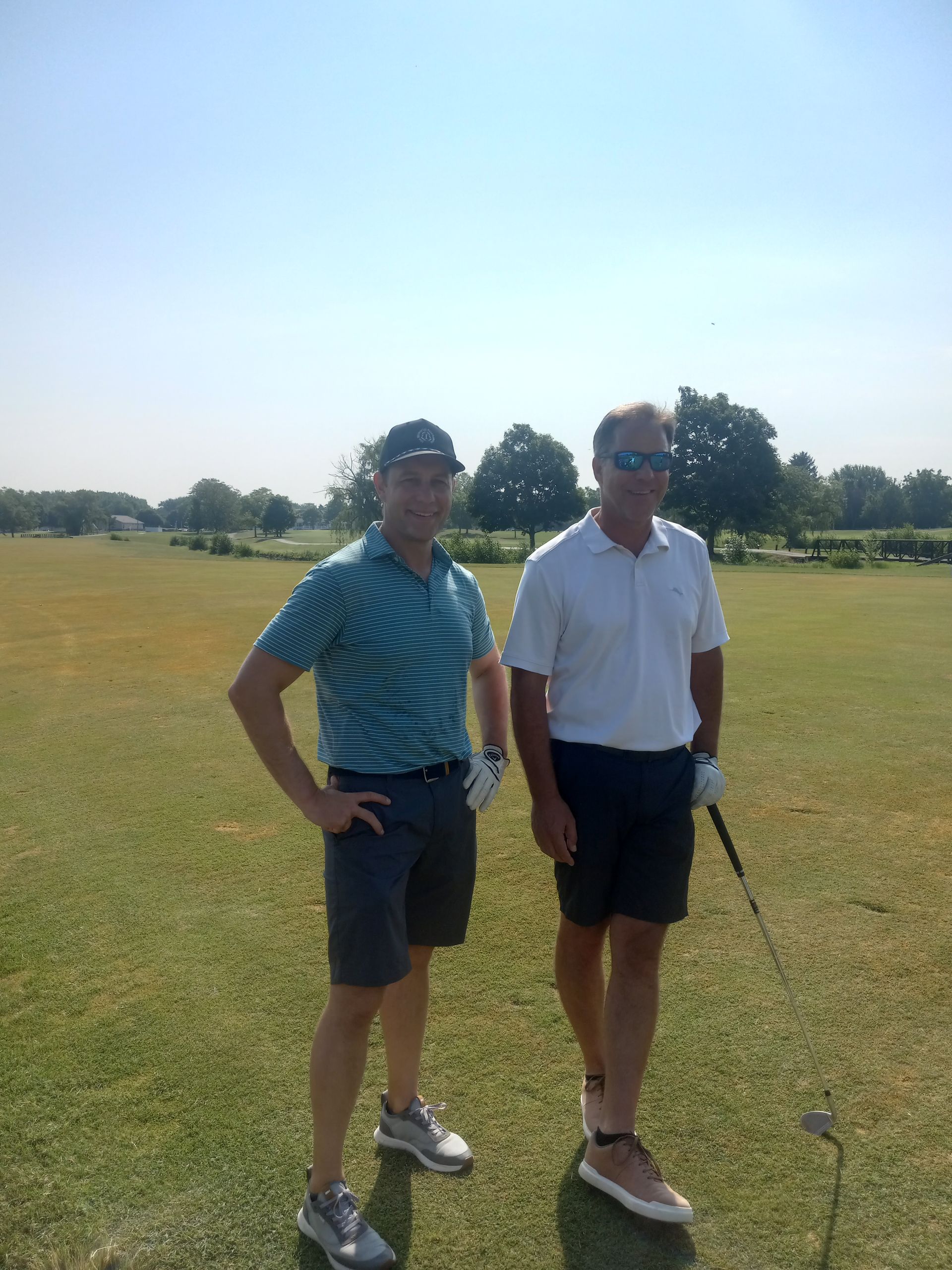 Two men standing next to each other on a golf course