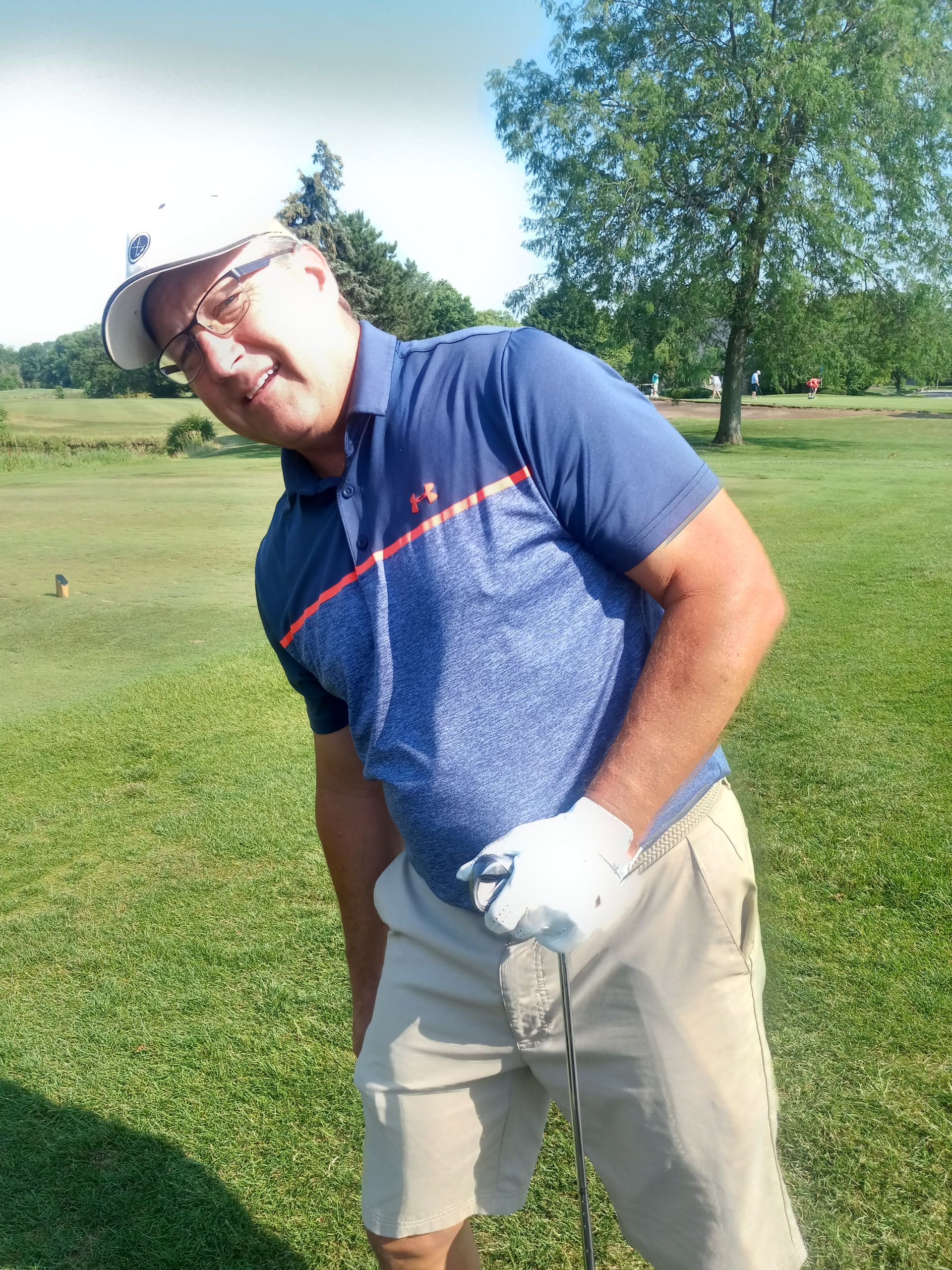 A man in a blue shirt is holding a golf club