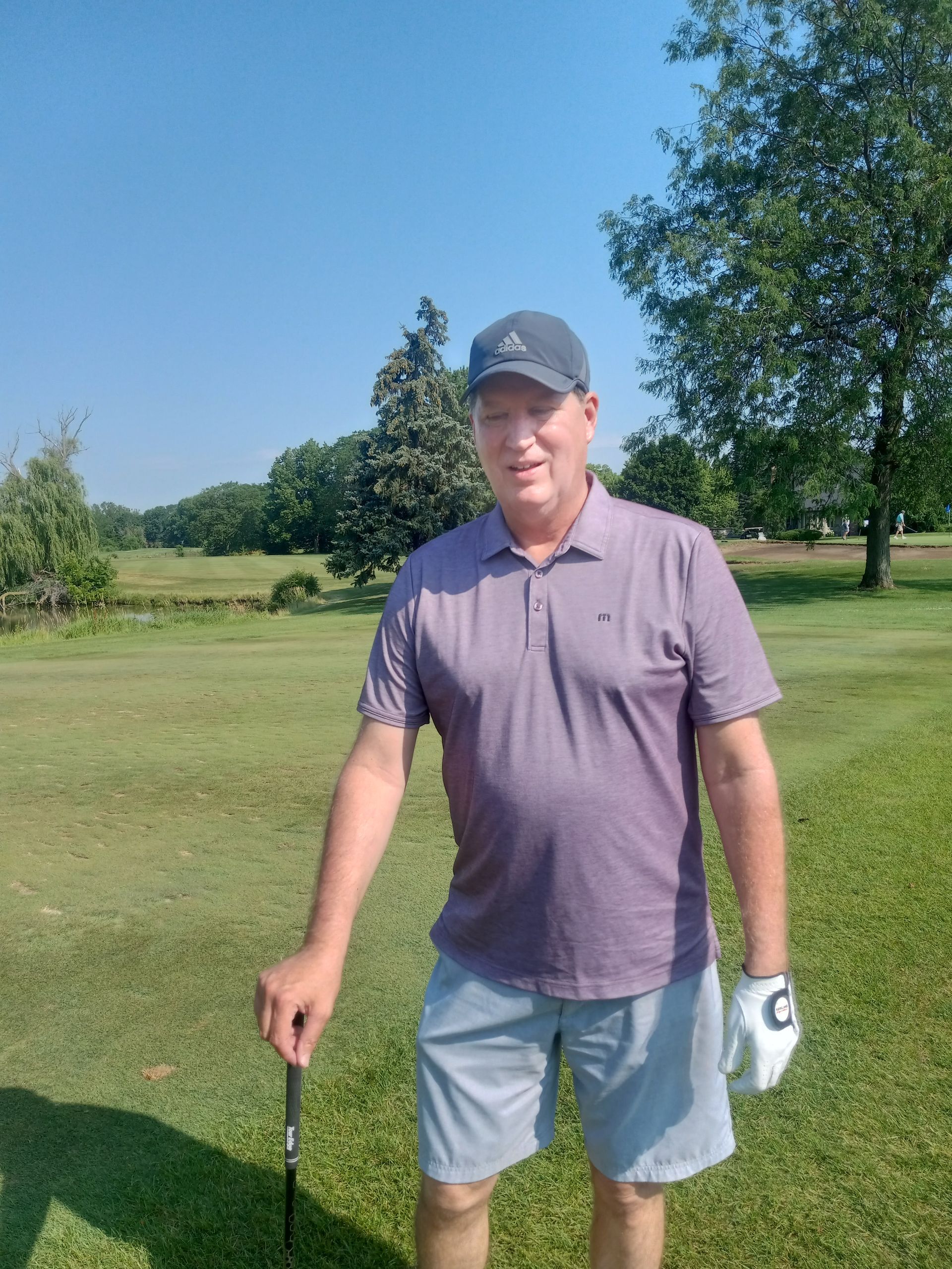 A man is standing on a golf course holding a golf club.