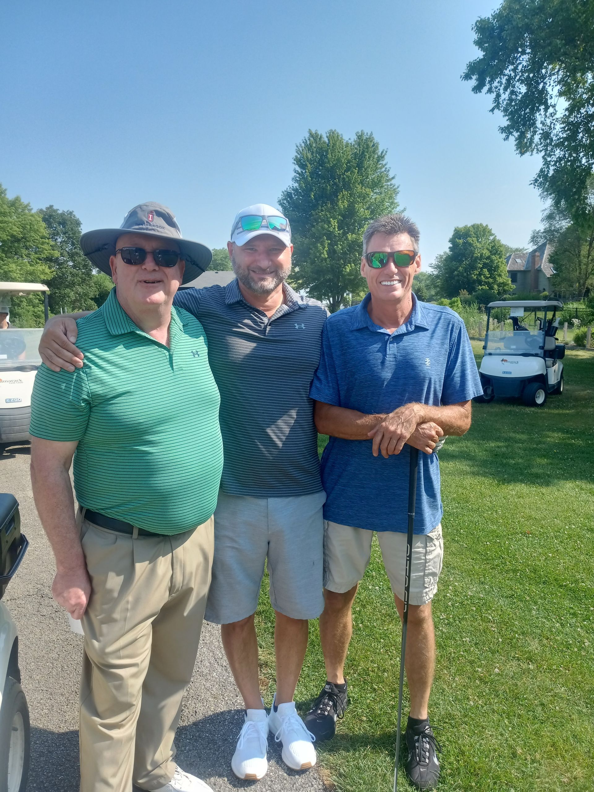 Three men are posing for a picture on a golf course.